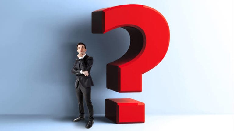 Thinking businessman next to a large question mark.