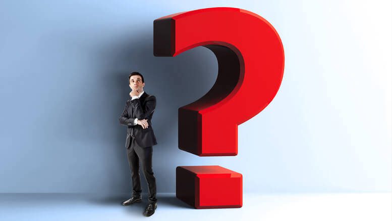 Thinking businessman next to a large question mark.