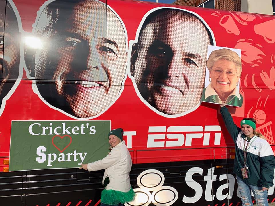 Photo shows people holding signs in front of a bus