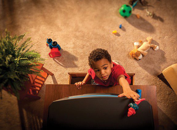 Image shows a child climbing up a dresser
