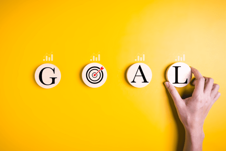 The word GOAL being set on a yellow wall with a hand and a bullseye