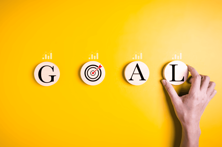 The word GOAL being set on a yellow wall with a hand and a bullseye